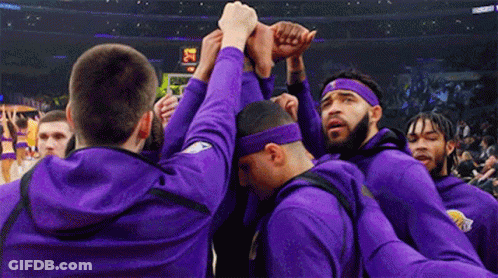 A Group Of Men Wearing Purple Sweatshirts And Headbands Are Huddled Together . GIF