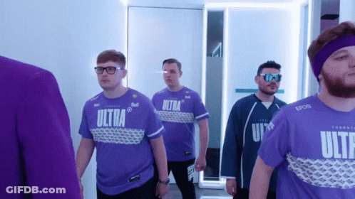 A Group Of Men Wearing Purple Ultra Shirts Are Walking Down A Hallway GIF