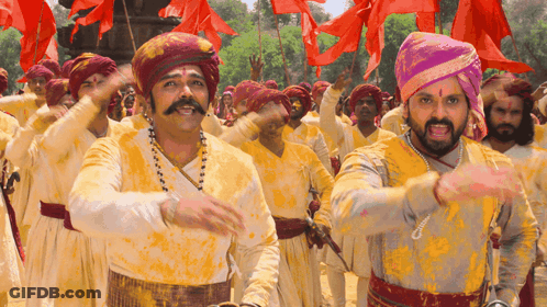 A Group Of Men Wearing Turbans And Yellow Shirts Are Dancing GIF