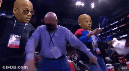 A Group Of Men With Masks On Their Faces Are Dancing In A Boxing Ring . GIF