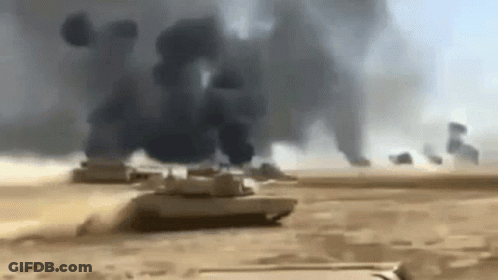 A Group Of Military Tanks Are Driving Through A Desert . GIF