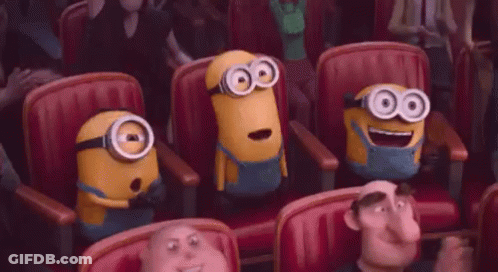 A Group Of Minions Are Sitting In A Row Of Red Chairs In A Theater . GIF