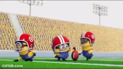 A Group Of Minions Wearing Helmets And Holding A Football On A Field GIF