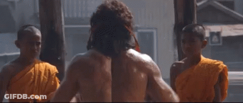 A Group Of Monks Are Standing Around A Shirtless Man Washing His Hair . GIF