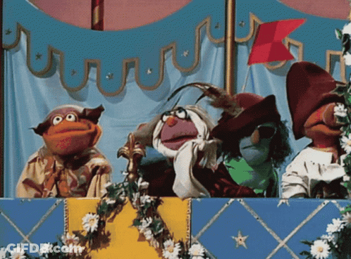 A Group Of Muppets Are On A Stage With Flowers And A Flag In The Background GIF