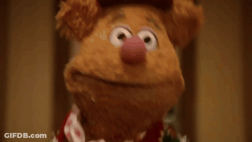 A Group Of Muppets Are Standing In A Hallway And One Of Them Is Wearing A Sweater That Says Muppets GIF