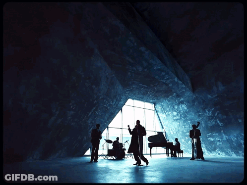 A Group Of Musicians Are Standing In Front Of A Large Window GIF