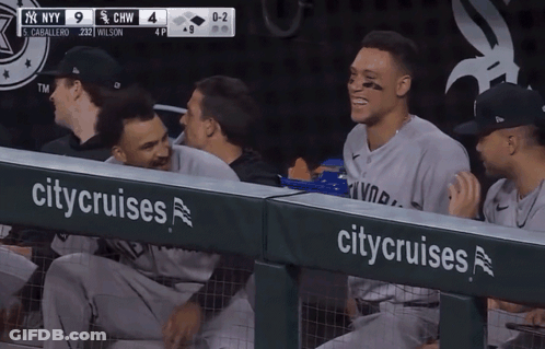 A Group Of Ny Yankees Players Sitting In The Dugout GIF