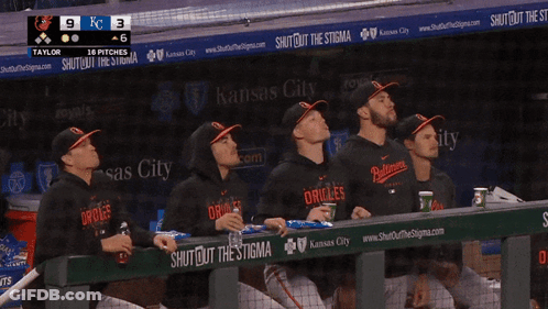 A Group Of Orioles Players Sit In The Dugout Watching The Game GIF