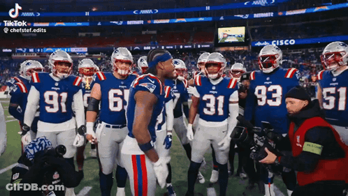 A Group Of Patriots Football Players Stand On The Field Talking To Each Other GIF