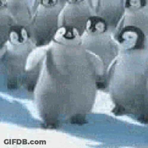 A Group Of Penguins Are Standing On Top Of A Snowy Surface . GIF