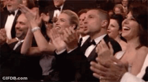 A Group Of People Are Applauding In A Theatre . GIF