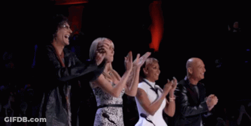 A Group Of People Are Applauding On A Stage . GIF
