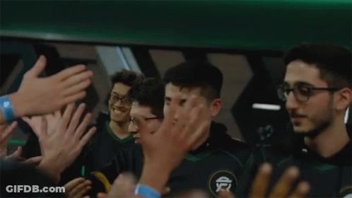 A Group Of People Are Clapping And Applauding A Man In A Green Shirt GIF