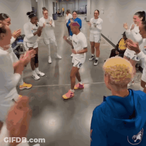 A Group Of People Are Clapping In A Hallway And One Of Them Is Wearing A Shirt That Says ' Nc State ' GIF
