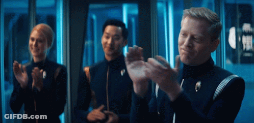 A Group Of People Are Clapping In Front Of A Sign That Says ' Exit ' GIF