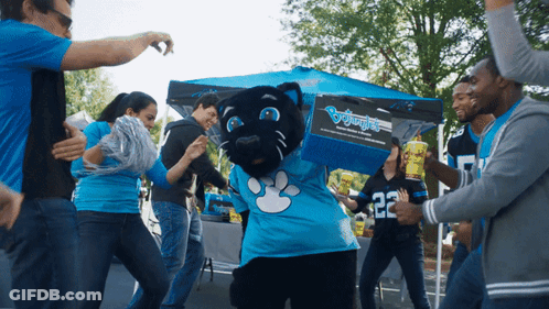 A Group Of People Are Dancing Around A Panther Mascot Wearing A Blue Shirt With The Number 22 On It GIF