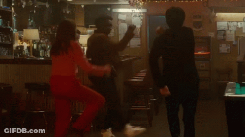 A Group Of People Are Dancing In A Bar While A Woman Stands On A Bar Stool . GIF