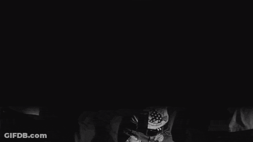A Group Of People Are Dancing In A Dark Room And One Of Them Is Holding A Bottle Of Beer GIF