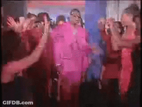 A Group Of People Are Dancing In A Dark Room And One Of Them Is Wearing A Pink Outfit GIF