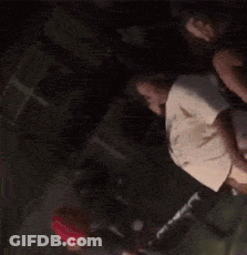 A Group Of People Are Dancing In A Dark Room While A Man Holds A Microphone . GIF