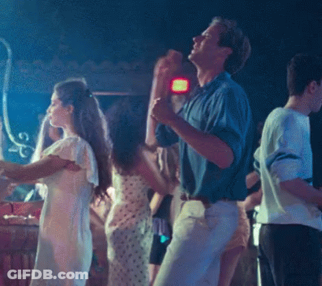 A Group Of People Are Dancing In A Dark Room With A Blue Light Behind Them GIF