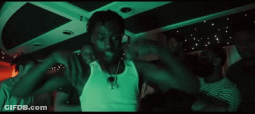 A Group Of People Are Dancing In A Dark Room With A Green Light Behind Them GIF