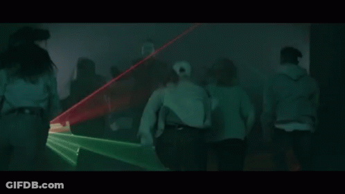 A Group Of People Are Dancing In A Dark Room With Green Lights Coming Out Of The Ceiling . GIF