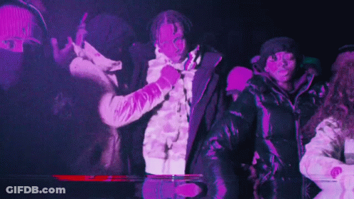 A Group Of People Are Dancing In A Dark Room With Purple Lights Behind Them . GIF