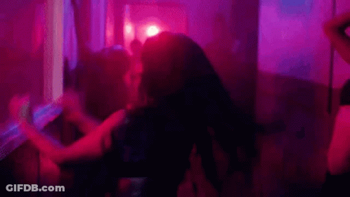 A Group Of People Are Dancing In A Dark Room With Purple Lights . GIF