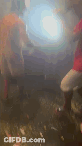 A Group Of People Are Dancing In A Dark Room With Smoke Coming Out Of The Ceiling . GIF