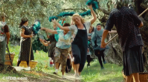 A Group Of People Are Dancing In A Field And One Woman Is Wearing Overalls GIF