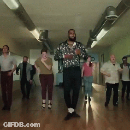 A Group Of People Are Dancing In A Hallway With A Man Wearing A Floral Shirt GIF