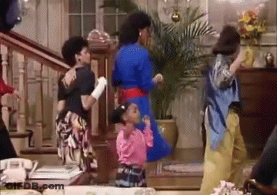 A Group Of People Are Dancing In A Living Room With Stairs . GIF