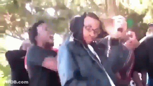 A Group Of People Are Dancing In A Park And One Of Them Is Wearing A Hoodie GIF