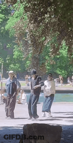 A Group Of People Are Dancing In A Park In Front Of A Fountain . GIF
