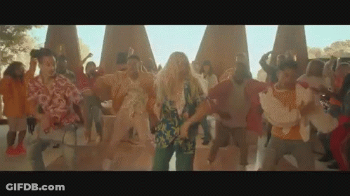 A Group Of People Are Dancing In A Park In Front Of A Large Group Of People . GIF