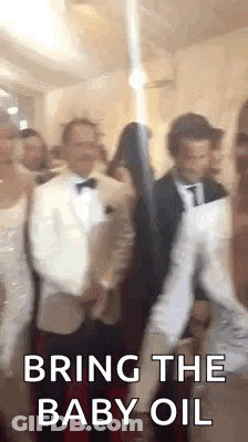 A Group Of People Are Dancing In A Room And One Of Them Is Holding A Baby Oil Bottle . GIF