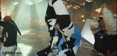 A Group Of People Are Dancing In A Room While A Man Is Holding A Flag . GIF