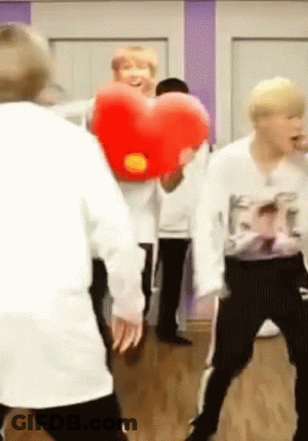 A Group Of People Are Dancing In A Room With A Red Heart Pillow . GIF