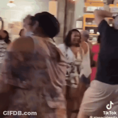A Group Of People Are Dancing In A Room With A Tiktok Logo On The Bottom Right GIF