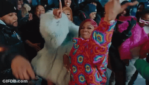 A Group Of People Are Dancing In A Room With A Woman Wearing A Colorful Jacket . GIF