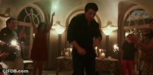 A Group Of People Are Dancing In A Room With Sparklers In The Background . GIF