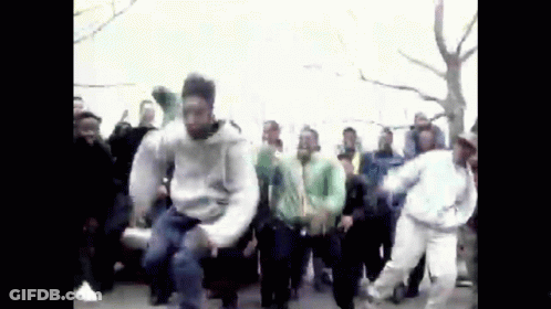 A Group Of People Are Dancing In A Street . GIF