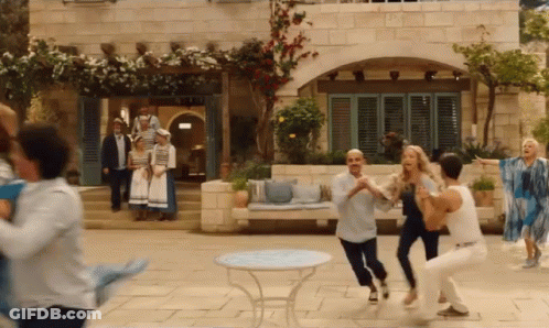 A Group Of People Are Dancing In Front Of A Building In A Movie . GIF