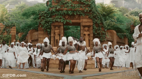 A Group Of People Are Dancing In Front Of A Building That Says Wanda Forever GIF