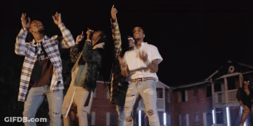 A Group Of People Are Dancing In Front Of A Building With The Letter S On The Front GIF