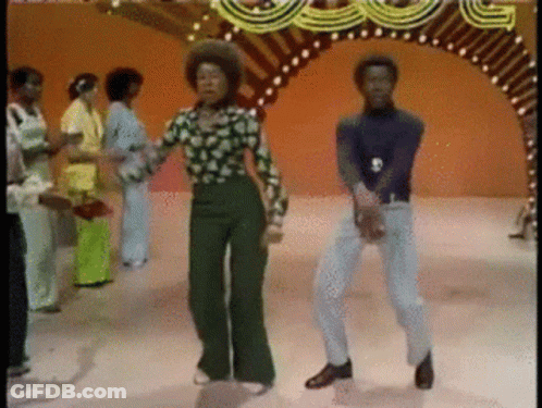 A Group Of People Are Dancing In Front Of A Carnival Arch GIF