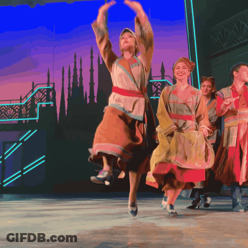 A Group Of People Are Dancing In Front Of A Castle GIF