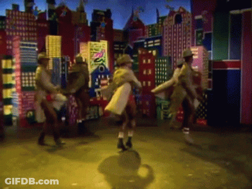 A Group Of People Are Dancing In Front Of A Cityscape With A Sign That Says Disco GIF